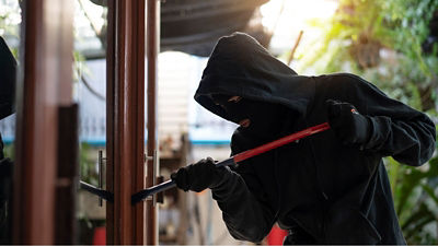 Photo d'un cambrioleur qui force une porte